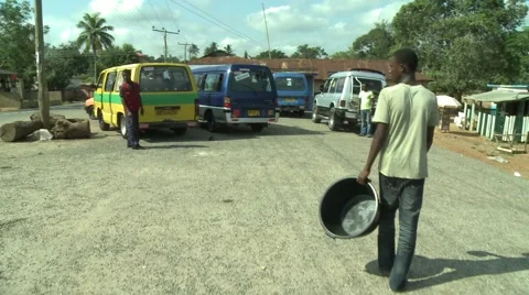 PAKRO YOUNG MAN CARRIES EMPTY WATER CONTAINER PAST VANS- CAMERA FOLLOWS Stock Footage 58930449