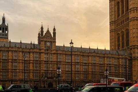 Palace of Westminster standing under a cloudy sky with street traffic passi.. Stock Photos