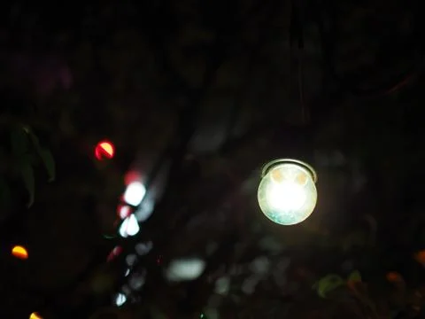 Pale blue light bulb hanging in the dark, small bokeh background Foto stock