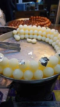 Pale rasgulla with silver leaf in warm market setting Stock-Fotos