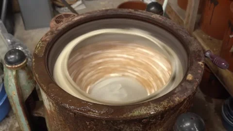 Pale shell buttons tumbling and swirling inside a rotating polishing pot seen 動画素材 347123869