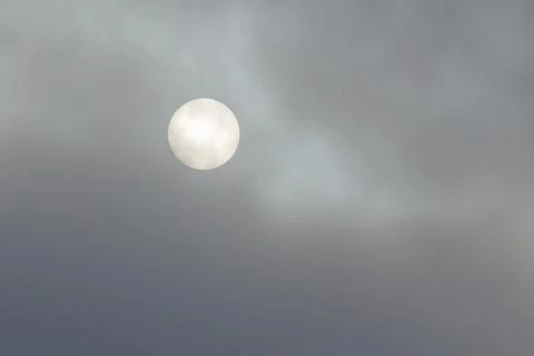 Pale sun shines through soft, drifting clouds. Gentle light filters through.. Stock Photos