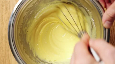 Pale yolk and sugar mixture is stirred slowly with whisk. Stock Footage 345273603