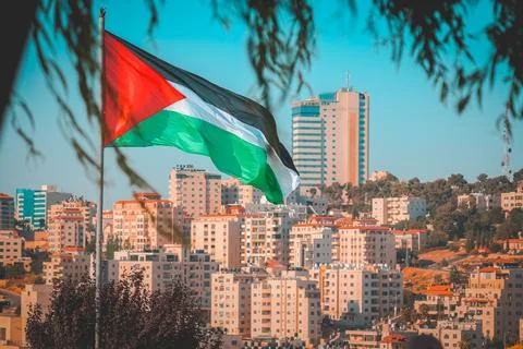 Palestine flag as through the tree with some city buildings at Ramallah Foto stock
