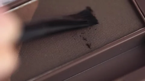 A palette with eyebrow shadow and a makeup brush. Brush gains dark brown ey.. Stock Footage 257466487