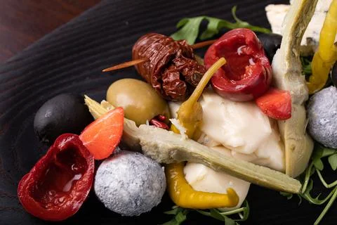 Palette of many types of cheese and some vegetables, tomatoes, paprika, olives. Stock Photos