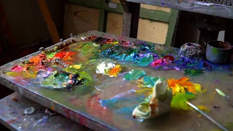 Palette with paints is on the table in the Studio. Multi-colored paint smeared Stock Footage 92165202