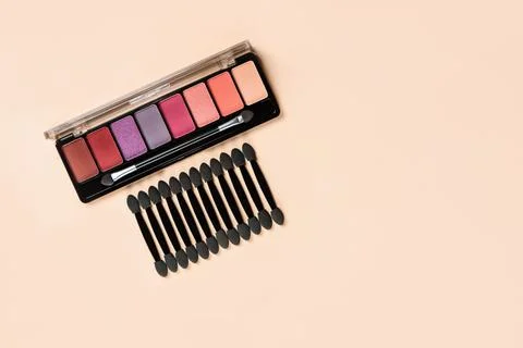 Palette of shadows with applicators on an orange background. Stock Photos