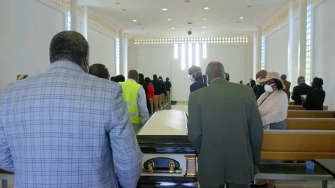 Pallbearers wheeling a coffin into the church while the congregation Video stock 136988490
