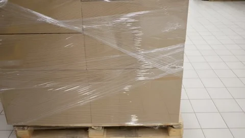 Pallet with cardboard boxes wrapped in polyethylene in warehouse or store hall. Stock Footage 285127390