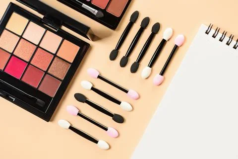 Pallet shadows and applicators with notepad on yellow background. Stock Photos