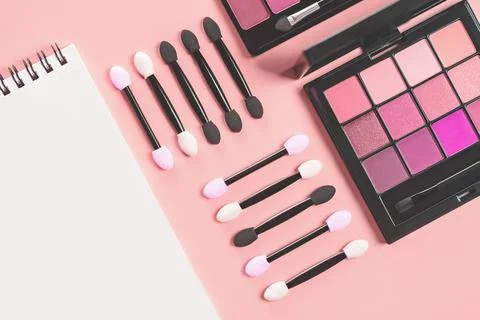 Pallet shadows and applicators with notepad on red background. Stock Photos