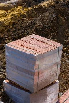 Pallets and packages of red bricks in a construction warehouse on the street. 写真素材