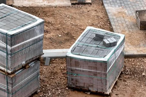 Pallets with gray paving slabs at a construction site. Plastic packaging prot 스톡 사진