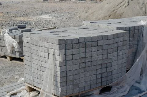 Pallets of gray paving tiles at the construction site. New cement blocks. Con Stock Photos