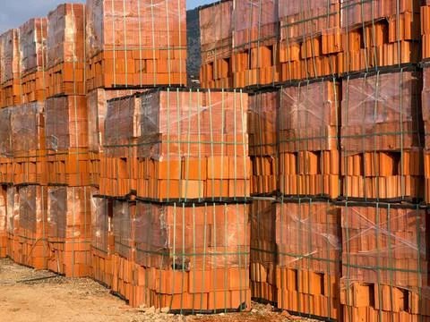 Pallets of red bricks wrapped in polyethylene and stand one on the other Stock Photos
