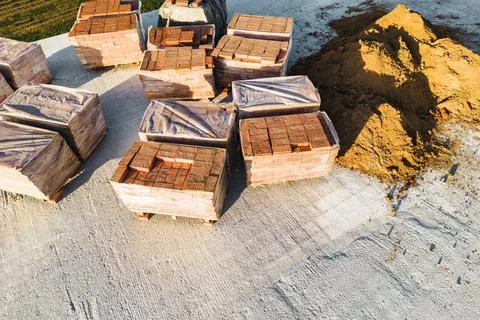 Pallets with red ceramic bricks on the roof of a building under construction. Stock Photos