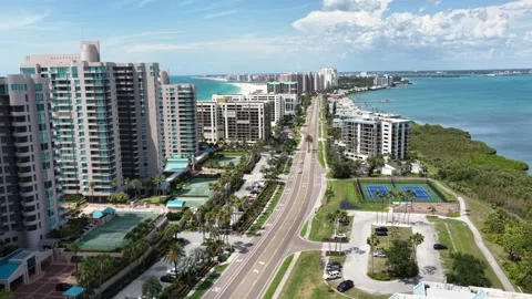 Palm-lined avenue runs between high-rise condo towers, tennis courts and Stock Footage 338408266