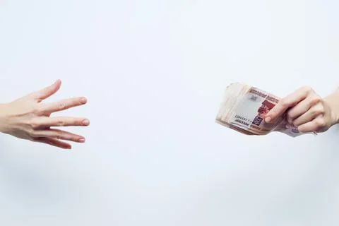 The palm reaches for a pack of five thousandth bills squeezed in the other hand Stock Photos