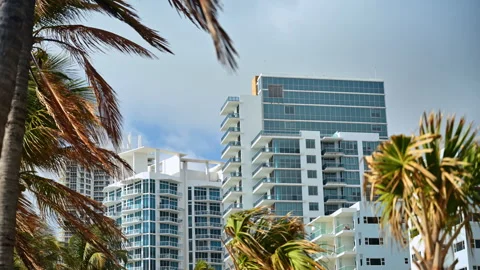 Palm trees and beautiful multi-storied buildings. Sky covered with clouds in the Stock Footage 332809922