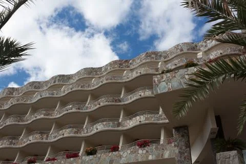 Palm trees in front of a wave-shaped hotel Stock Photos
