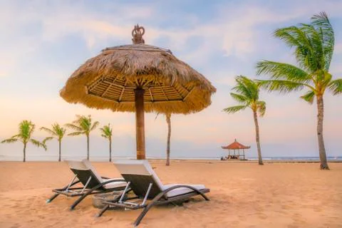 Palm trees on white sandy beach, two sunbed and parasol. View of nice tropica Foto stock