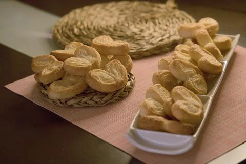 Palms of puff pastry on white rectangular plate and wicker plate Stock Photos
