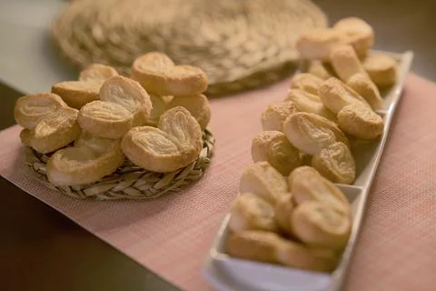 Palms of puff pastry on white rectangular plate and wicker plate Stock Photos