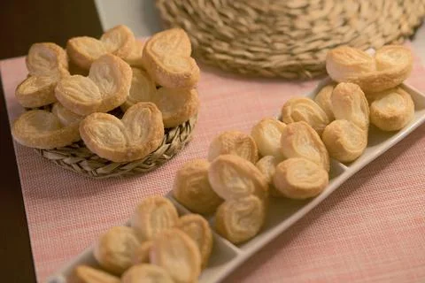 Palms of puff pastry on white rectangular plate and wicker plate Stock Photos