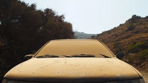 Pan across an abandoned car covered in dirt on a dry, dusty road Stock Footage 92208755