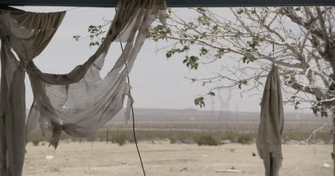 Pan Across Broken Window to Tattered Curtains Stock Footage 89943170