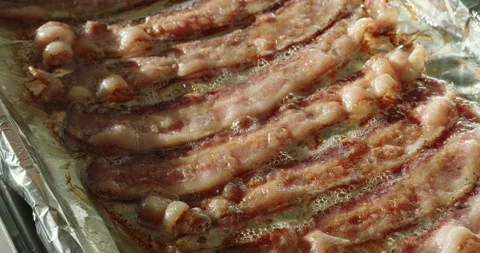 Pan across cooked bacon on cookie sheet fresh out of the oven Stock Footage 303512222