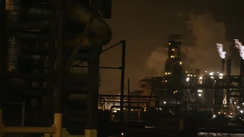 Pan across industrial landscape with flames and smoke from factory at night Stock Footage 89945334