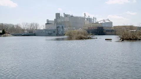 Pan across the river looking at buildings and houses in a small town. 4k60p Stock Footage 128849541