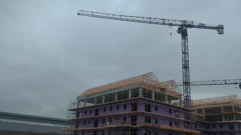 Pan Across Tower Crane Constructing New Apartment Buildings with Scaffolding Stock Footage 333943779