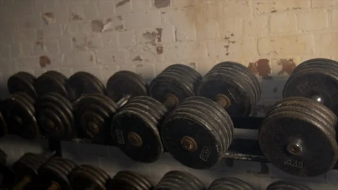 Pan Across Of Weights Lined Up On Weight Rack In Industrial Gym Old Style Vidéo 123066163