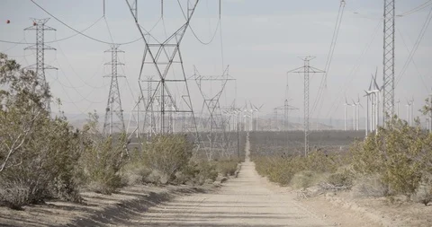 Pan Across Wide Shot of Power Lines and Wind Mills in California Desert - Right Stock Footage 89942524