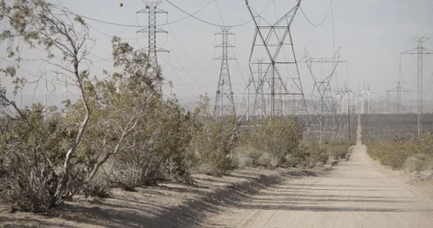 Pan Across Wide Shot of Power Lines and Wind Mills in California Desert - Left Stock Footage 89942528