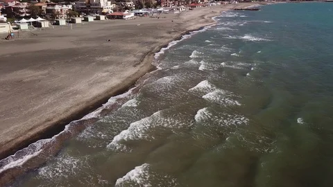 Pan aerial view of the sand beach of Tarquinia with buildings in the distance Stock Footage 106537092