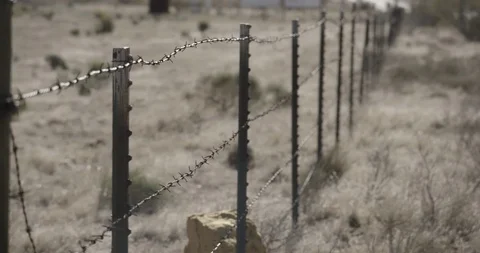 Pan Along Barbed Wire Fence in Desert Meadow with Rack Focus Stock Footage 89942663