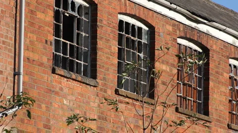 Pan along the windows of a closed and derelict factory building  England UK Vídeos de archivo 935644