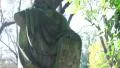 Pan up and down of Jesus stone statue in a graveyard, in the sun silhouette HD Footage