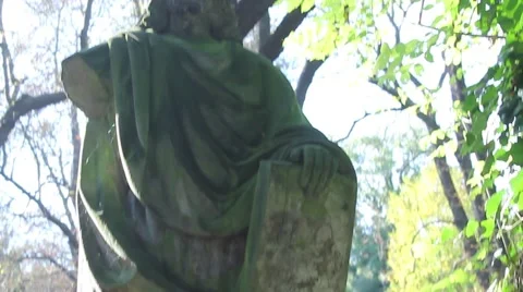 Pan up and down of Jesus stone statue in a graveyard, in the sun silhouette Stock Footage 42333695