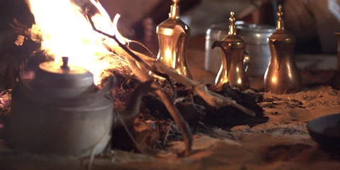Pan up to Arabic men sitting and talking around a camp fire at night. Stock Footage 46870558