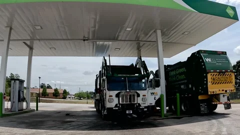 Pan around of Waste management trash trucks filling up at a Natural Gas Stock Footage 180134042
