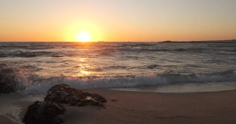 Pan up on beach at sunset from sand to ocean Stock Footage 131888540