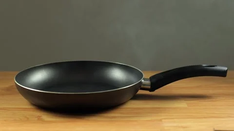 The pan is black on the table. A frying pan Stock Footage 273286896