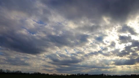 Pan of a blue sky with dark storm clouds and sun rays beaming through the clo Video stock 149053744
