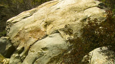 Pan from boulder to cascading stream and old stone walls Stock Footage 87671797