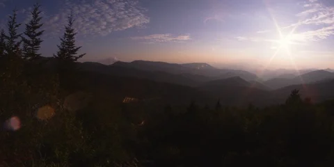 Pan of bright sunlight shining over the mountains and forest at sunrise Stock-Footage 103399275